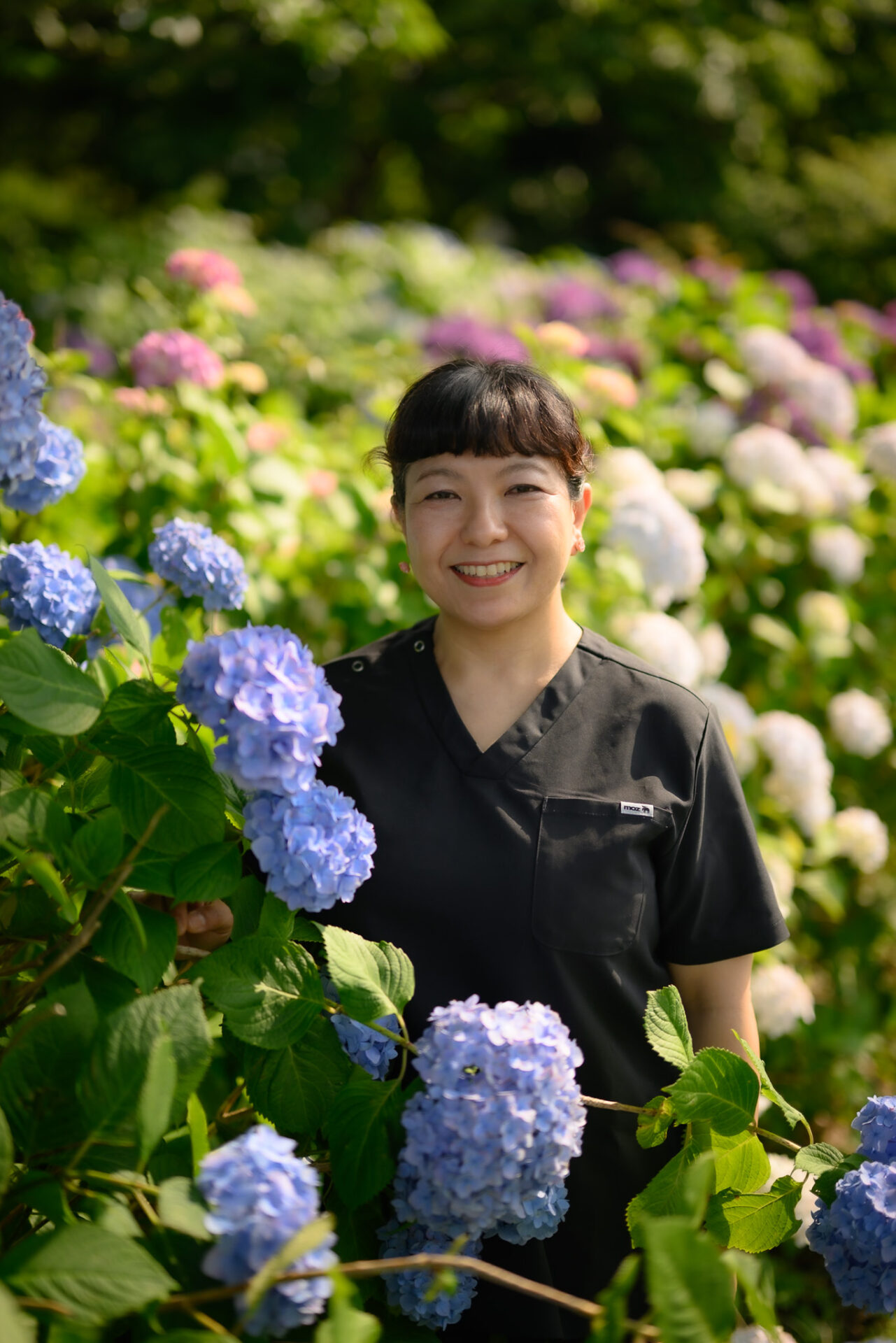 紫陽花のそばで笑顔を見せるセラピスト・宮野美佐緒さん